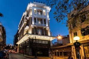 un edificio blanco alto en una calle de la ciudad por la noche en Athens Mansion Luxury Suites, en Atenas