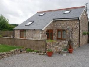 a small stone house with a gravel driveway at Ty Gylfinir in Llandegla