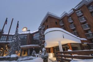 Un edificio ricoperto di neve con un albero di Natale davanti di Appartement 35m² Domaine du Jardin Alpin a Courchevel