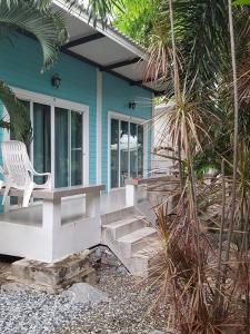 a blue house with a white chair on the porch at Charlie's Bungalows in Ko Si Chang