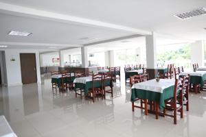 un comedor con mesas y sillas con mantel verde en Hotel Mansão dos Nobres, en São João da Boa Vista