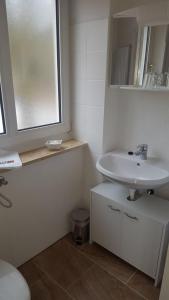 ein weißes Bad mit einem Waschbecken und einem Fenster in der Unterkunft Waldhotel Zollhaus in Nürnberg