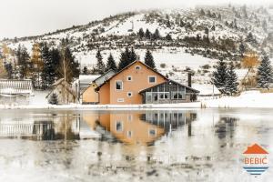 dom w śniegu obok wody w obiekcie Lake House Bebić w mieście Kupres