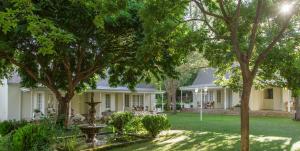 a white house with trees in the yard at Rosenhof Boutique Hotel in Oudtshoorn