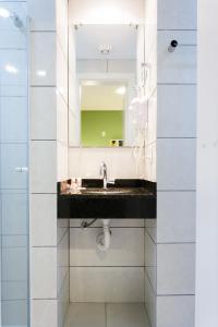 La salle de bains est pourvue d'un lavabo et d'un miroir. dans l'établissement Hotel Sol By MRHotelaria, à Curitiba