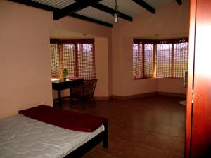 a bedroom with a bed and a table and windows at Relaxing 2 B/R Estate House, Deenaty, Tamil Nadu in Coimbatore
