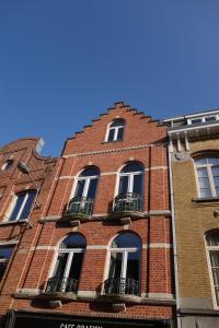 - un bâtiment en briques rouges avec des fenêtres et des balcons dans l'établissement Temps de Pose, à Ypres