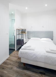 a bedroom with a large white bed and a glass door at Bordo'Appart Hoya Bella in Arcachon