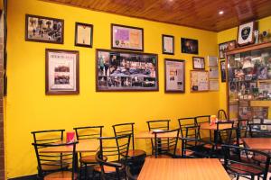 a restaurant with yellow walls and wooden tables and chairs at Mikotania in Covilhã +41 photos