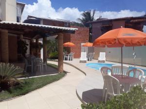 a patio with a table and chairs and an umbrella at Pousada Ilha Mar in Barra de Santo Antônio