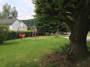 un parque infantil en un patio con un árbol en Ferienwohnung an der Burg, en Windeck