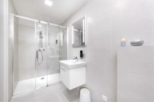 a white bathroom with a shower and a sink at DownTown Suites Belohorska in Prague