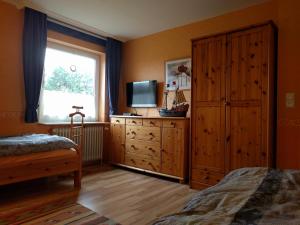 a bedroom with a bed and a dresser with a television at Whg Suedblick auf Föhr in Goting