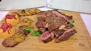 uma tábua de corte de madeira com bife e batatas em Hôtel Restaurant Alios em Bas-Mauco