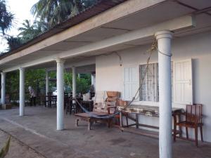 a porch with a hammock and chairs on a house at Pandan Beach Homestay in Kampong Pandan