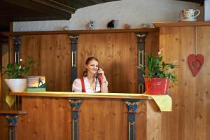 Una donna seduta al bancone che parla al cellulare di Hotel & Restaurant Zum Karpfen a Obernburg am Main