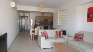 a living room with two white couches and a kitchen at Pyla Gardens A102 in Pyla
