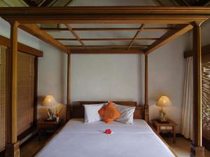 a bedroom with a large bed with two lamps at Puri Bagus Manggis in Candidasa