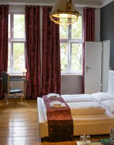 a bedroom with a bed and a chair and windows at ArtHotel Connection in Berlin