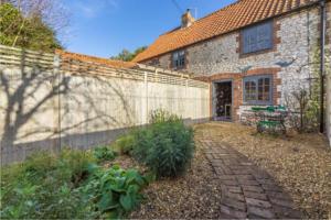 a brick building with a fence next to a garden at No33 THORNHAM BOUTIQUE COTTAGE 3 in Thornham