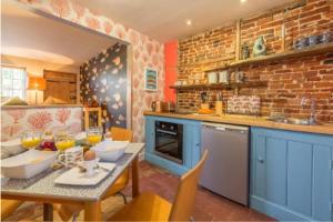 a kitchen with blue cabinets and a table with chairs at No33 THORNHAM BOUTIQUE COTTAGE 3 in Thornham