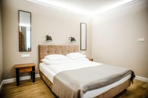 a bedroom with a large white bed with two mirrors at Pokoje Amore Residence in Płock