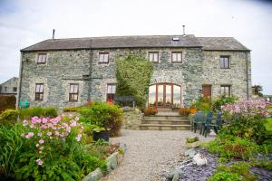 an old stone house with a garden in front of it at Storws Y Gorlan Shepherd's Hut in Valley