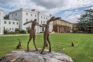 a statue of two people on a rock in a field at De Vere Beaumont Estate in Windsor