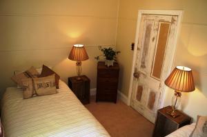 a bedroom with a bed with two lamps and an open door at Eagle's View Cottage - Yarra Valley in Wandin North