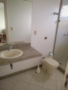 een badkamer met een wastafel, een toilet en een spiegel bij Hospedagem Sol e Mar in Vila Velha