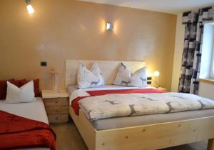 a bedroom with a bed with white and red sheets at Ferienwohnung Pramstaller in Valdaora