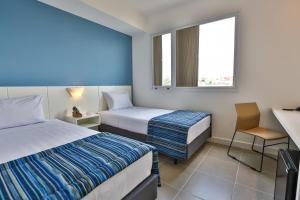 um quarto de hotel com duas camas e uma secretária em Transamerica Fit Jacareí em Jacareí