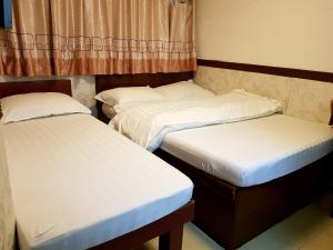 2 camas individuales en una habitación con sofá cama en Astronaut's Hotel en Hong Kong