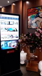 a computer monitor sitting on a desk with a vase of flowers at Art Hotel Eiffel in Paris