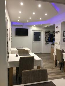 House Zupan في غاكوفيتسا: غرفة طعام مع طاولات بيضاء وكراسي وتلفزيون