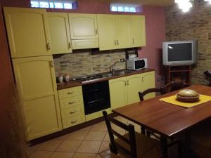 uma cozinha com armários amarelos, uma mesa e uma televisão em Casa Signorile em Càbras