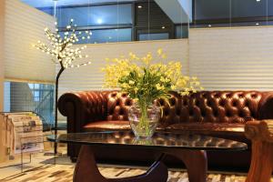 un jarrón de cristal con flores amarillas sobre una mesa en Hotel Las Terrazas Business, en Chillán