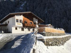 una casa en una montaña cubierta de nieve con una valla en Appartement O. Tom's Hütte, en Neustift im Stubaital