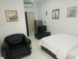 a bedroom with a bed and a chair and a television at J. I. T HOTEL in Chaltlāng