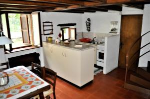 eine Küche mit einer Spüle, einem Kühlschrank und einem Tisch in der Unterkunft Rustico Gola di Lago in Lelgio