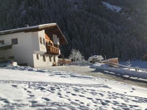a house in the snow with a mountain at Appartement O. Tom's Hütte in Neustift im Stubaital