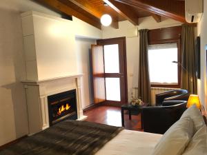 a living room with a fireplace and a bed at Hotel Del Lago in Puigcerdà