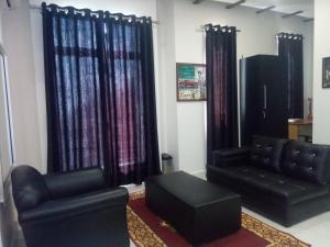 a living room with black furniture and purple curtains at J. I. T HOTEL in Chaltlāng