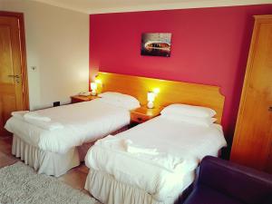 two beds in a hotel room with red walls at King's Head Inn in Llangennith