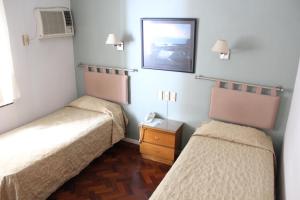 een kamer met 2 bedden, een tafel en een spiegel bij Ayacucho Palace Hotel in Buenos Aires