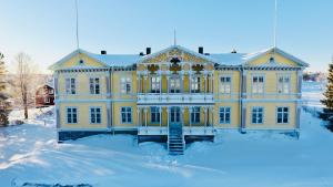 Una gran casa amarilla con nieve en el suelo en Filipsborg, the Arctic Mansion en Kalix
