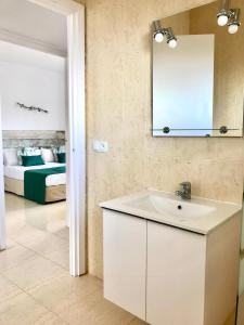 baño con lavabo, espejo y cama en Apartamentos Las Palmeras en Palmanova