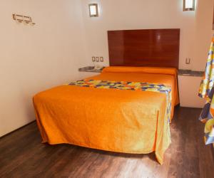 2 camas con sábanas de color naranja en una habitación en Las Avenidas, en Pachuca de Soto