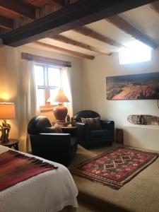 a bedroom with a bed and chairs and a window at Old Taos Guesthouse B&B in Taos