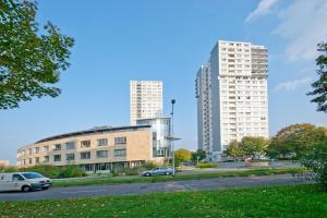 zwei hohe Gebäude in einer Stadt mit Autos auf der Straße in der Unterkunft GWG City Apartments III in Halle-Neustadt